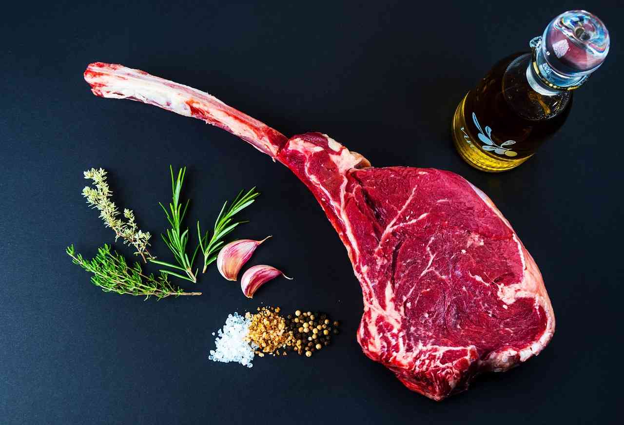 Premium tomahawk ribeye steak with fresh herbs, garlic, sea salt, peppercorns, and olive oil on a black background, representing Commercial Kitchen Financing, Catering Growth Capital, Franchise Restaurant Financing, Restaurant Construction Loans, and Restaurant Capital Providers that help upscale steakhouses expand operations, upgrade kitchens, and grow their hospitality businesses.