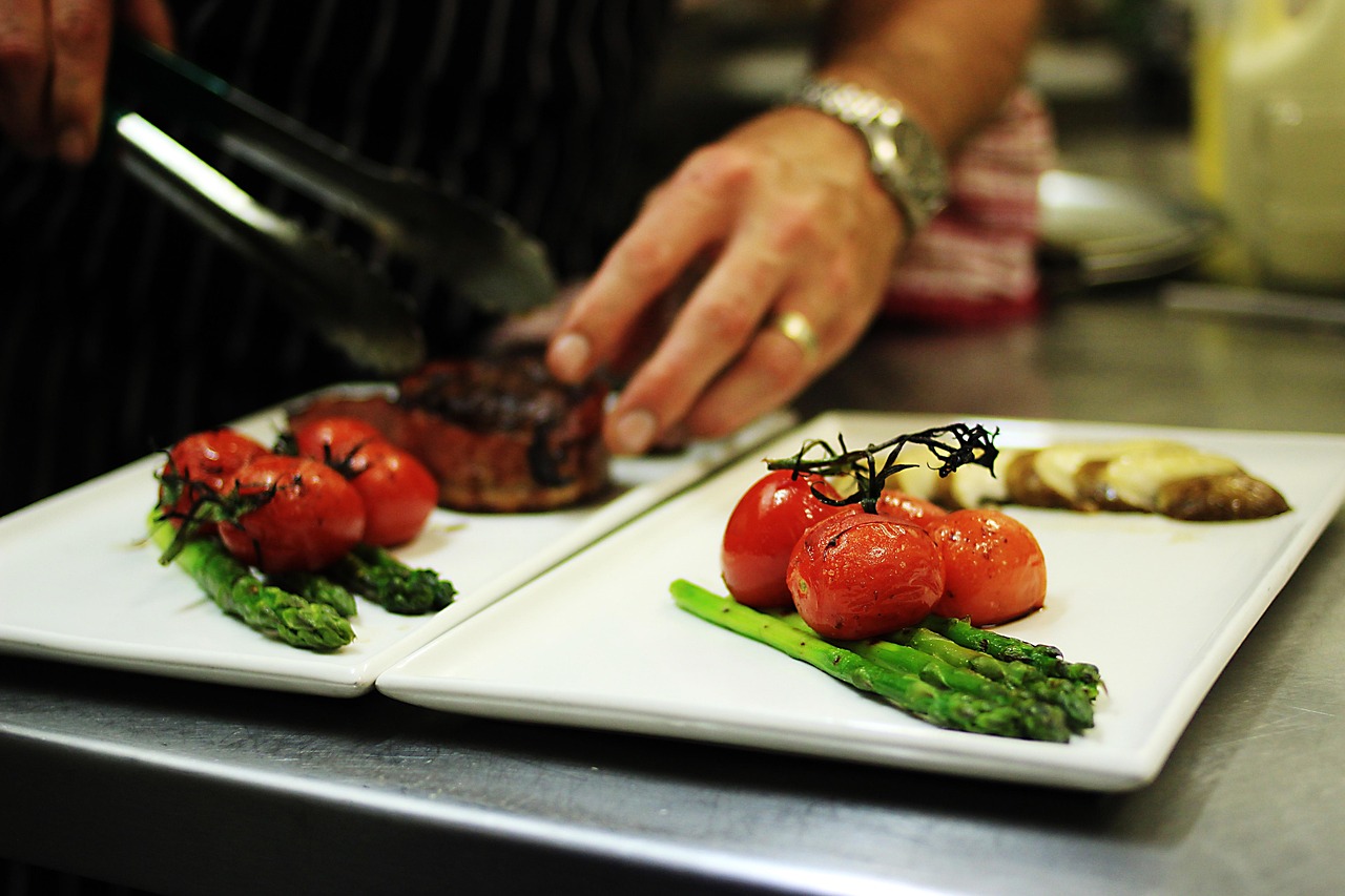 Professional chef plating gourmet meals in a commercial kitchen, demonstrating restaurant operations that may utilize Catering operation expansion loans, financing commercial kitchen equipment, restaurant digital ordering financing, and restaurant liquidity financing to support catering growth, equipment upgrades, online ordering systems, and working capital needs.
