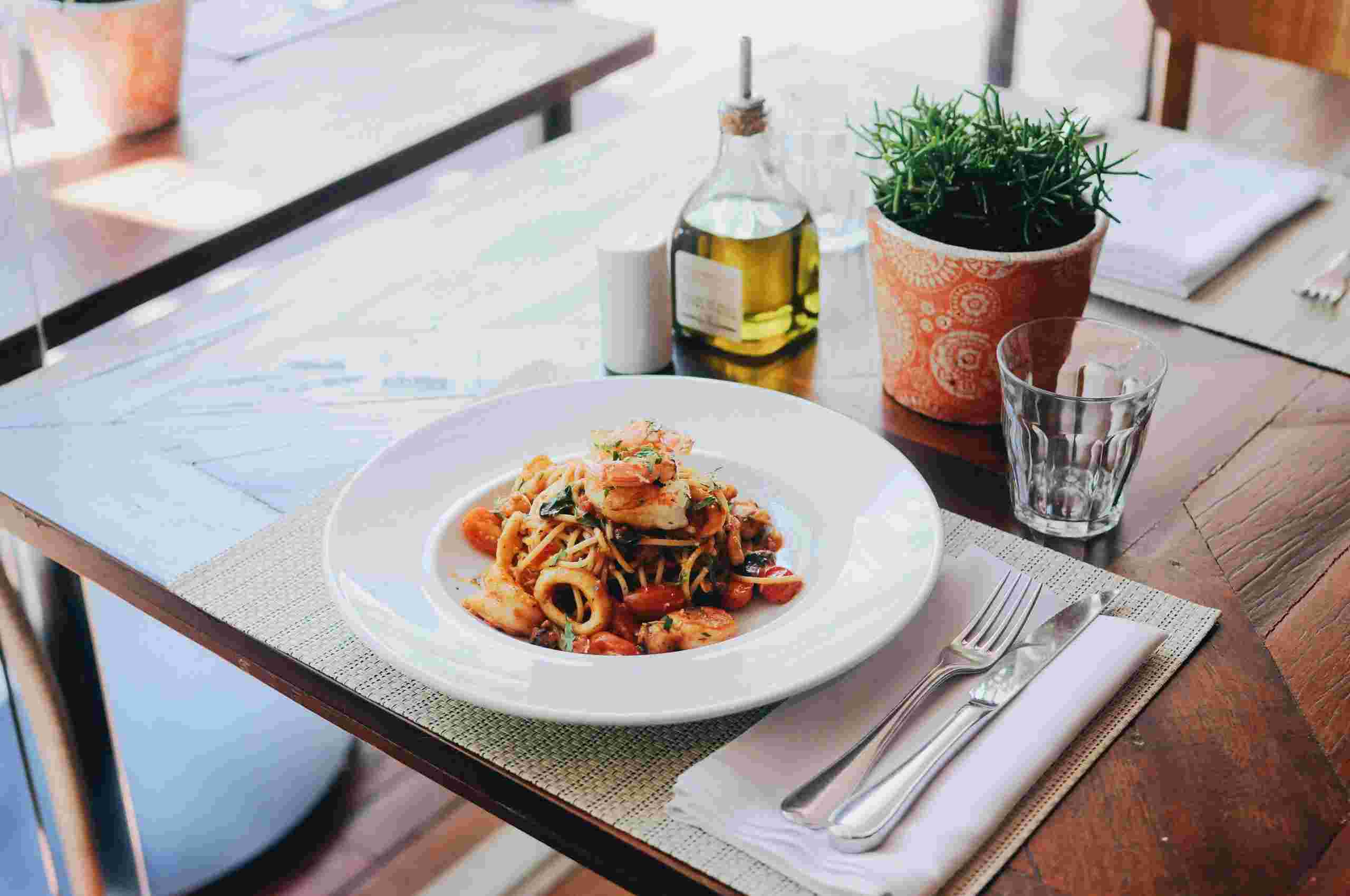 Elegant seafood pasta entrée served in a modern restaurant dining environment, illustrating Restaurant Inventory Loans, QSR Growth Financing, Fast Food Restaurant Financing, Restaurant Onboarding Financing, and Restaurant Financing Options for restaurant owners seeking capital for inventory management, employee training, expansion, and operational growth.