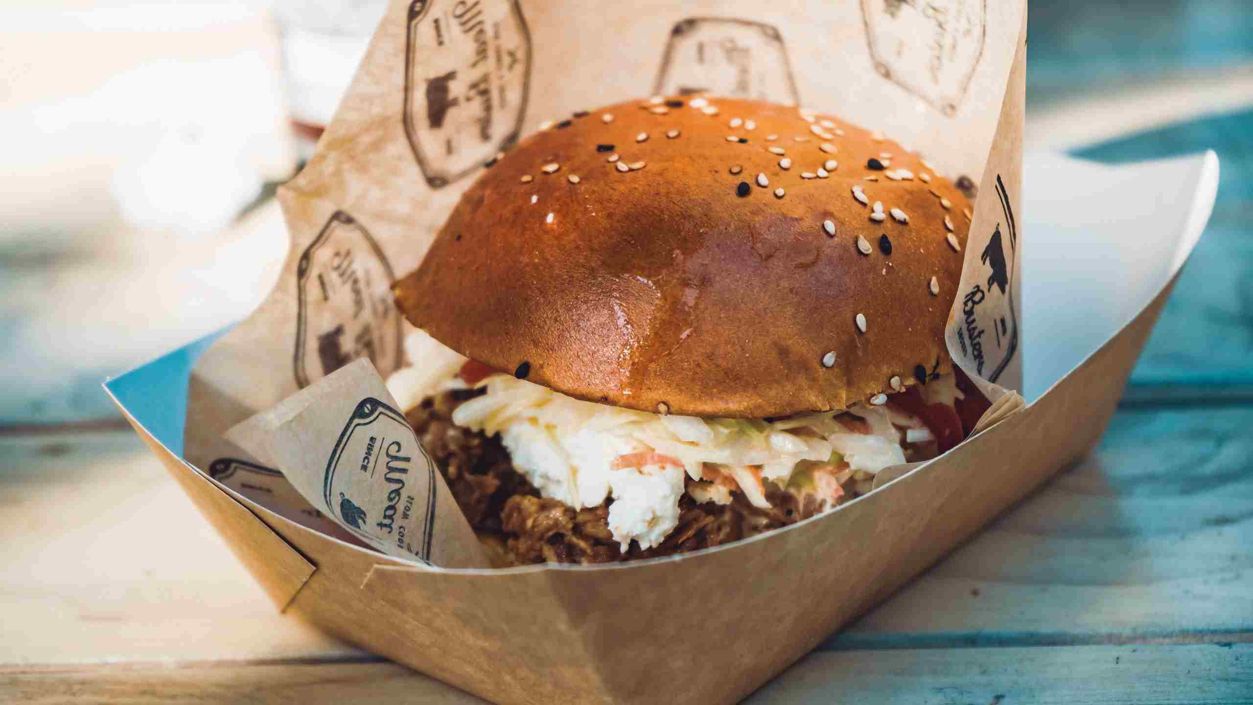 Gourmet burger served in branded packaging at a quick-service restaurant, representing Restaurant Line of Credit, Restaurant Hiring Capital, Restaurant Purchase Financing, Restaurant Acquisition Funding, and Drive Thru Construction Financing for restaurant owners seeking funding for growth, staffing, acquisitions, and operational expansion.