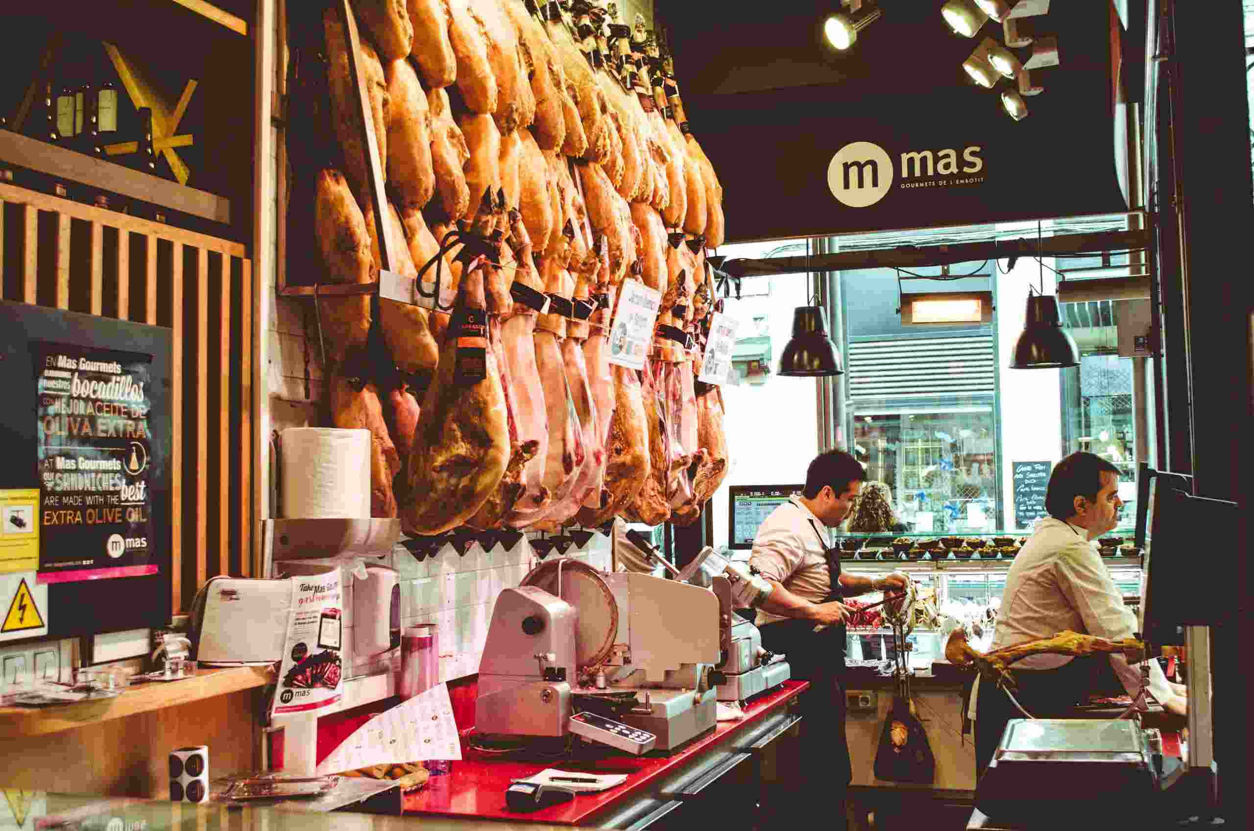 Restaurant interior featuring cured meats, commercial food preparation equipment, and staff at work, representing Restaurant Startup Loans, New Restaurant Financing, Restaurant Business Startup Capital, Restaurant Location Expansion Loans, and Restaurant Business Expansion Loans for growing food service businesses.